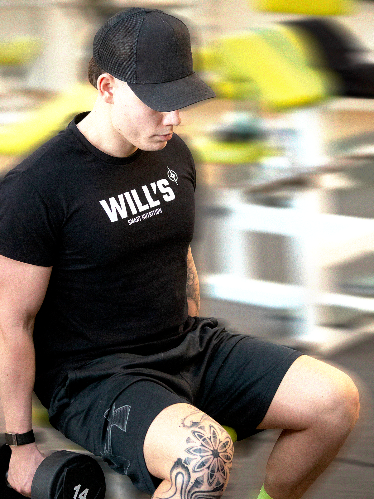 Person wearing a black 'WILL'S' t-shirt sitting outdoors and working out.